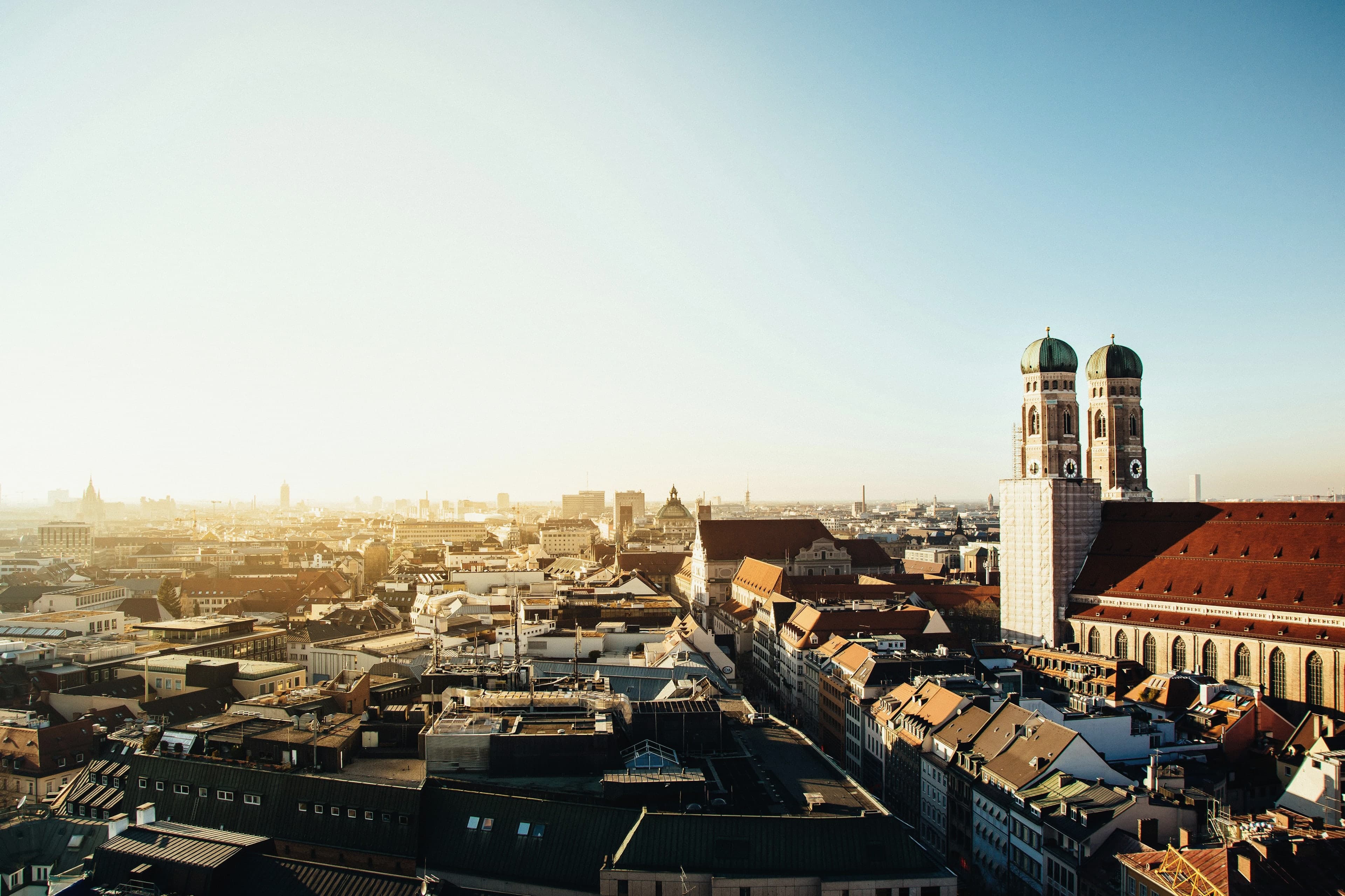 View across the rooftops of Munich old town in morning light, the towers of the Frauenkirche on the right